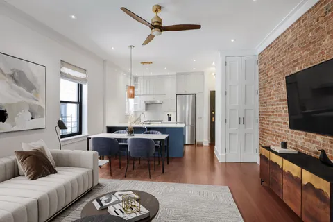 a living room with furniture a flat screen tv and kitchen view