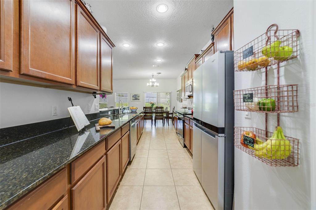 352 Giovani Boulevard Clermont, FL 34715 - Photo 9 of 46 a hallway with a dining table chairs and a refrigerator