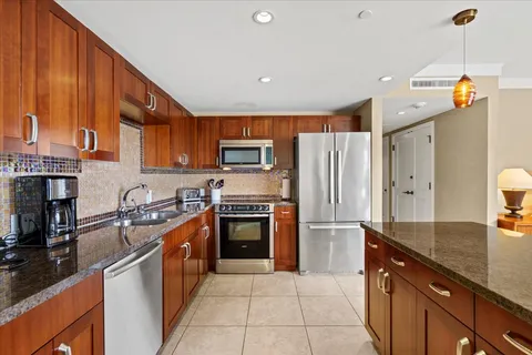 a kitchen with stainless steel appliances granite countertop a refrigerator a stove and a sink