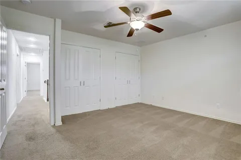 an empty room with closet and a ceiling fan
