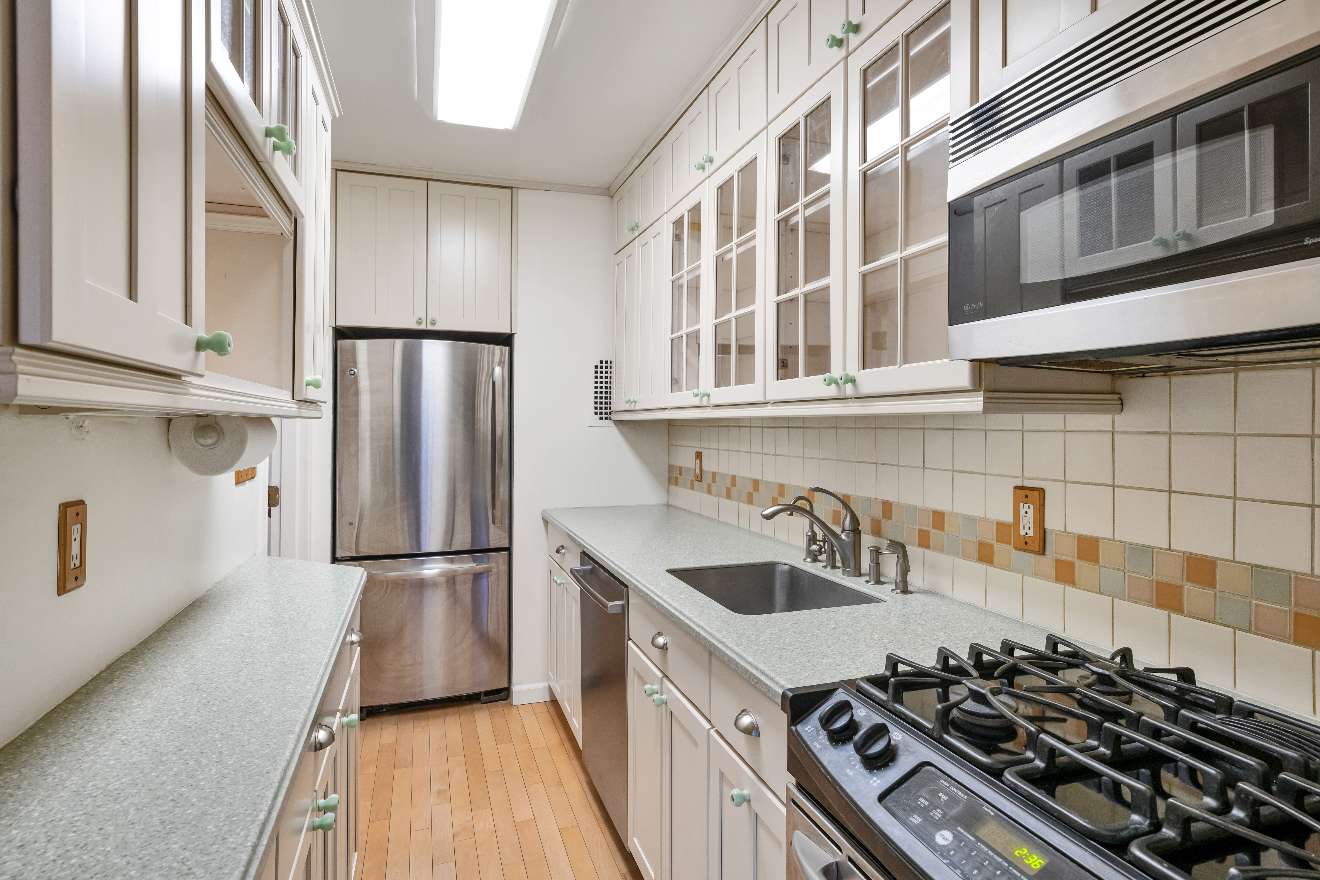 345 East 52nd Street, Unit 8G Manhattan, NY 10022 - Photo 2 of 9 a kitchen with stainless steel appliances a refrigerator a sink and wooden cabinets