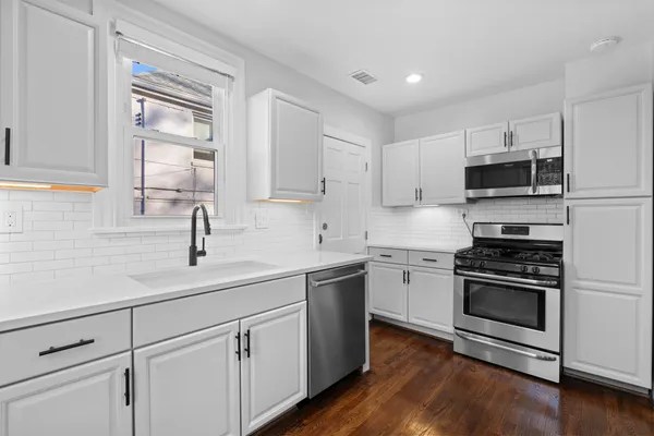 a kitchen with cabinets stainless steel appliances a sink and wooden floor