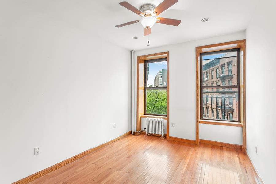56 MacDougal Street, Unit 16 Manhattan, NY 10012 - Photo 4 of 6 an empty room with wooden floor fan and windows