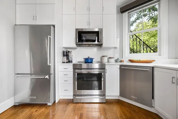 a kitchen with a refrigerator stove and wooden floor