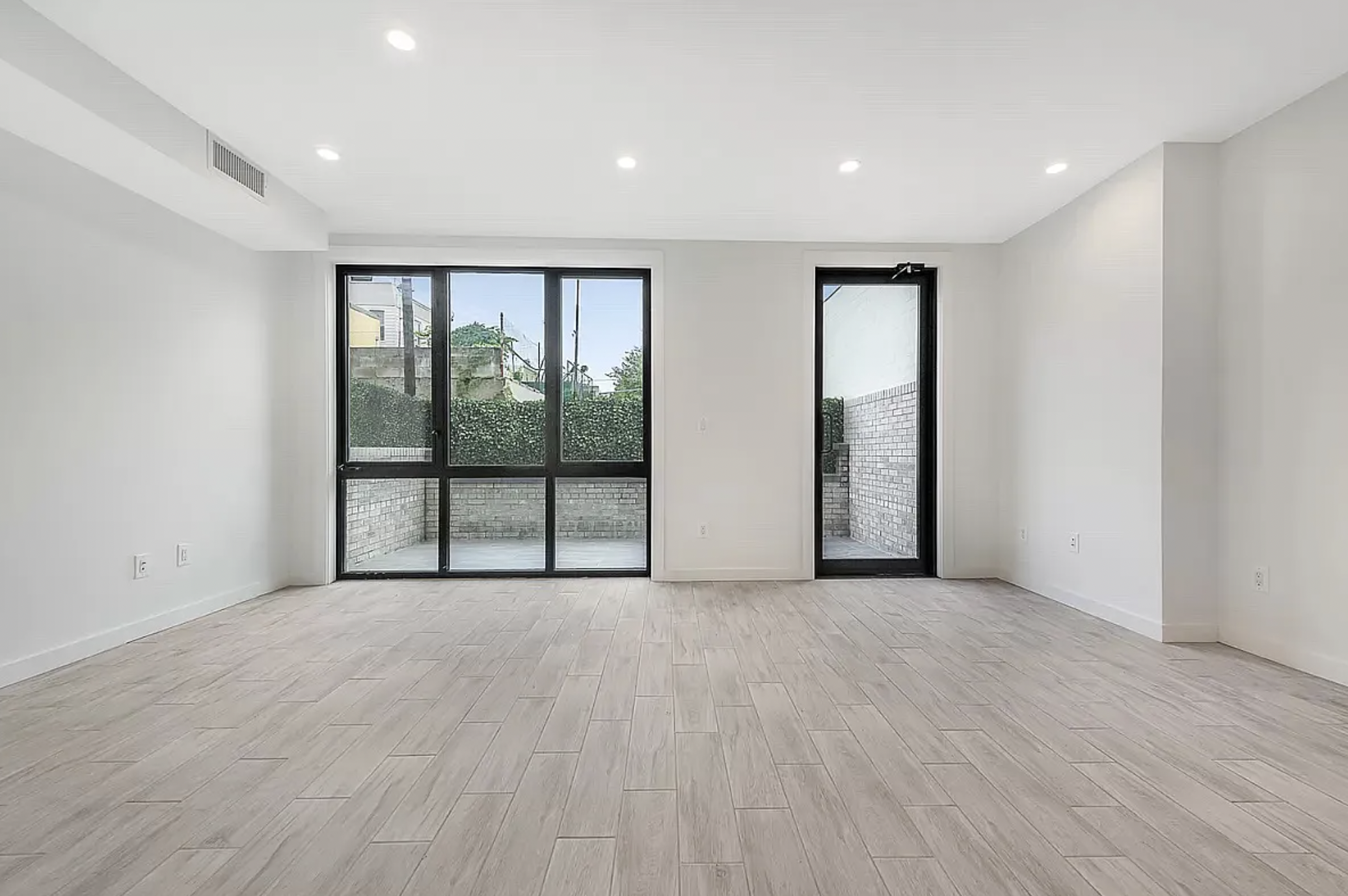 14-11 31st Avenue, Unit 1B Queens, NY 11106 - Photo 4 of 9 a view of an empty room with wooden floor and a window