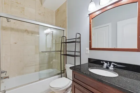 a bathroom with a granite countertop sink toilet a mirror a bathtub and shower