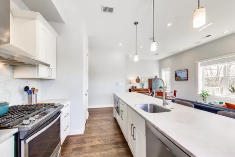 a kitchen with kitchen island a stove a sink a center island and windows