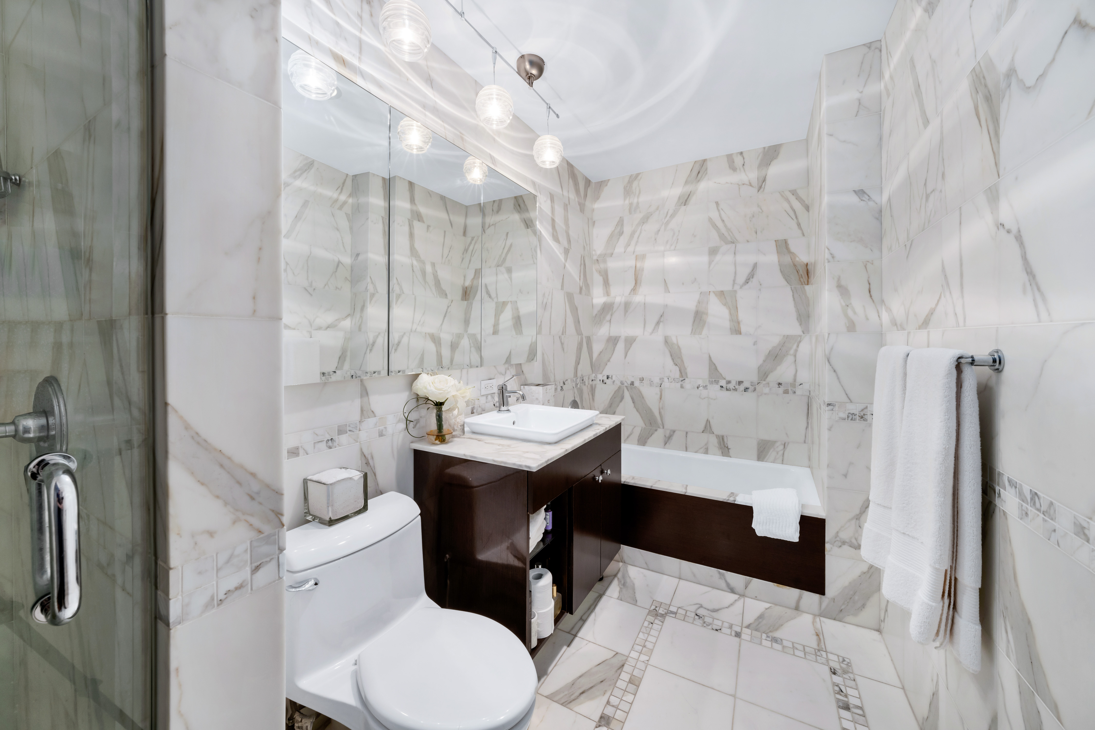 212 East 57th Street, Unit 5C Manhattan, NY 10022 - Photo 8 of 10 a bathroom with a sink a toilet a mirror and shower