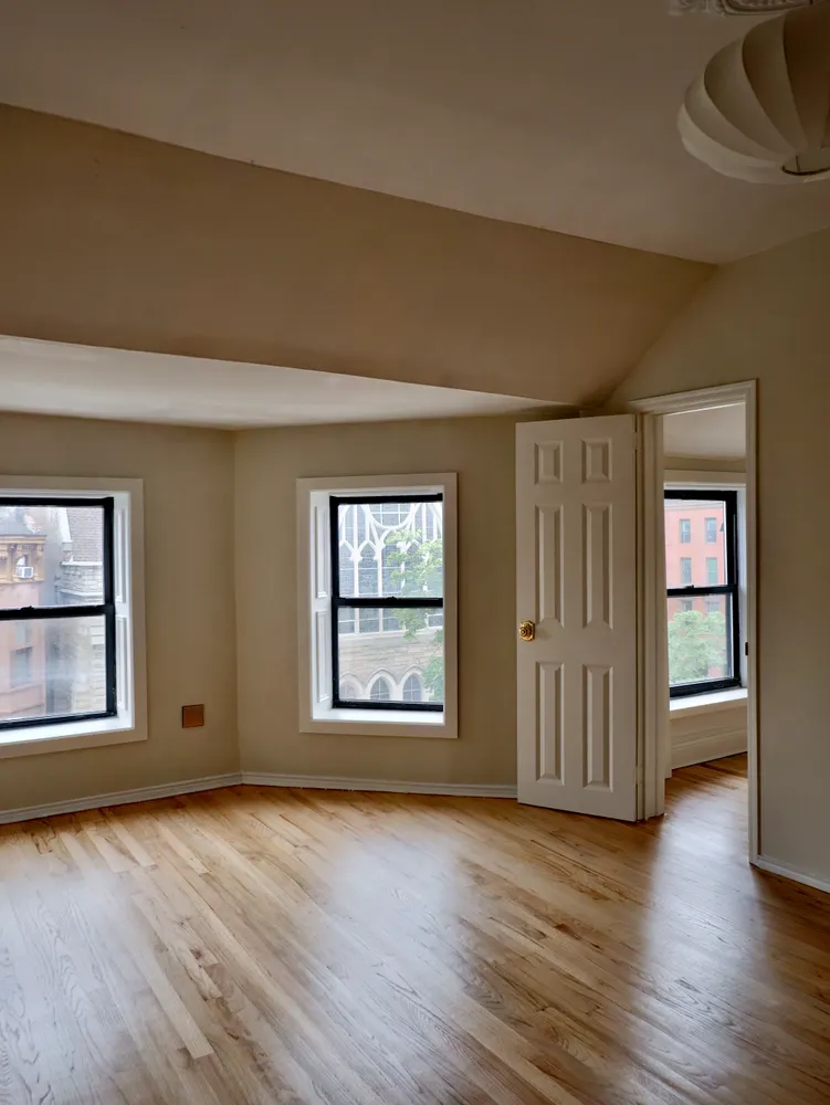 an empty room with wooden floor and windows