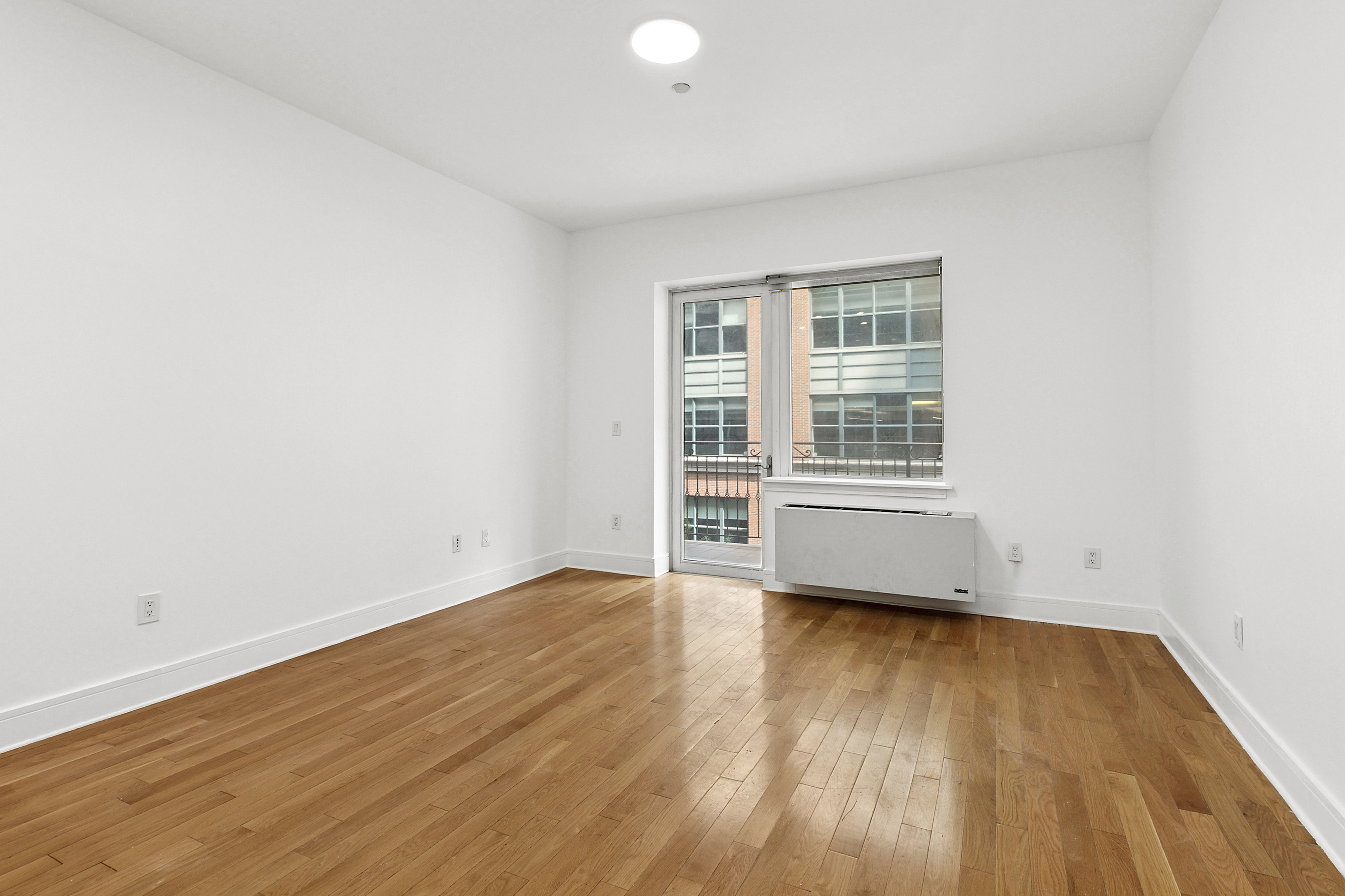 41-26 27th Street, Unit 4H Queens, NY 11101 - Photo 4 of 21 an empty room with wooden floor and windows