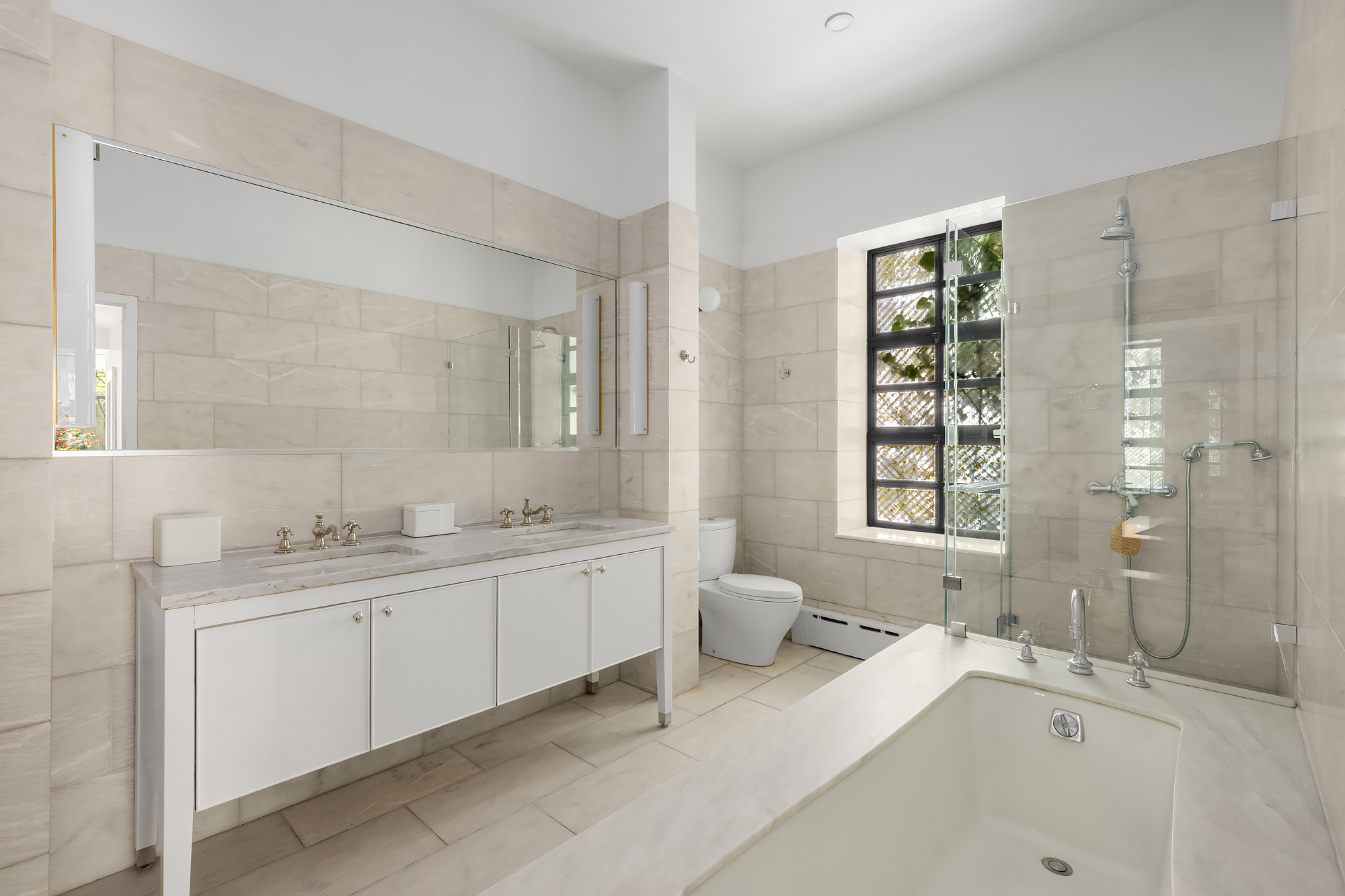 134 Charles Street Manhattan, NY 10014 - Photo 9 of 10 a spacious bathroom with a granite countertop sink mirror and a bathtub
