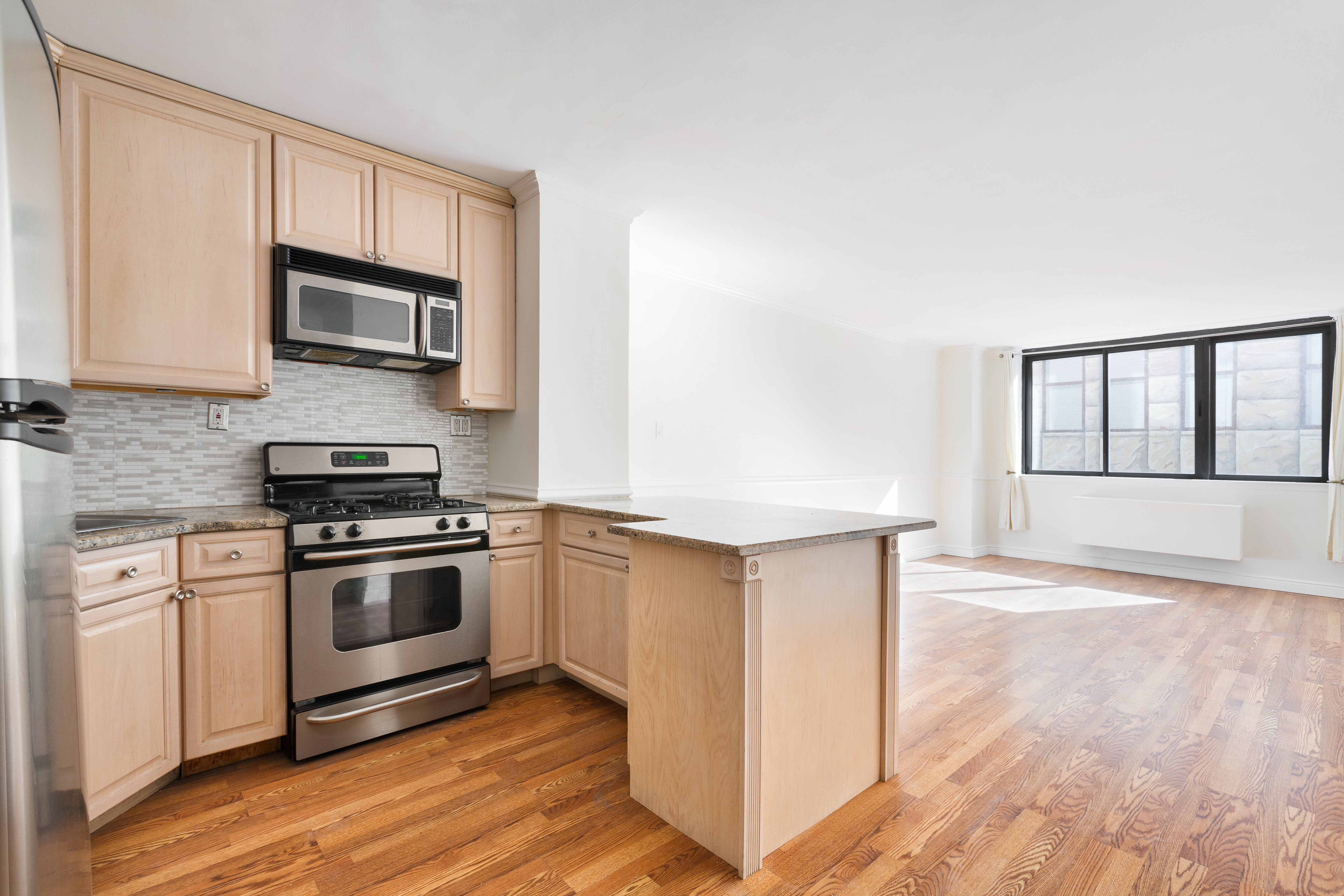 280 Park Avenue South, Unit 4F Manhattan, NY 10010 - Photo 3 of 7 a kitchen with stainless steel appliances granite countertop a stove a microwave and a white cabinets