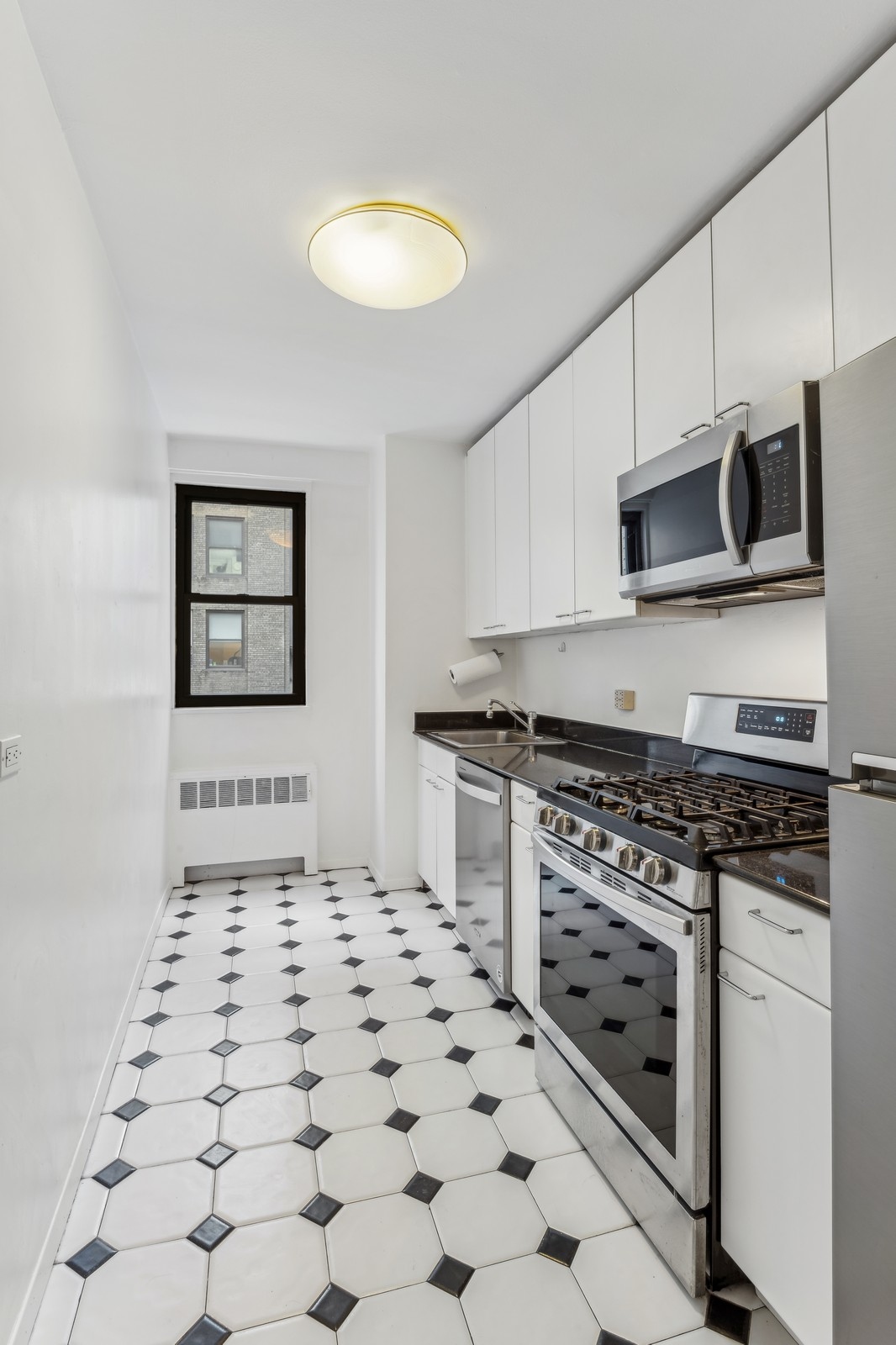 116 Central Park South, Unit 7C Manhattan, NY 10019 - Photo 4 of 6 a kitchen with stainless steel appliances a stove a sink and a microwave