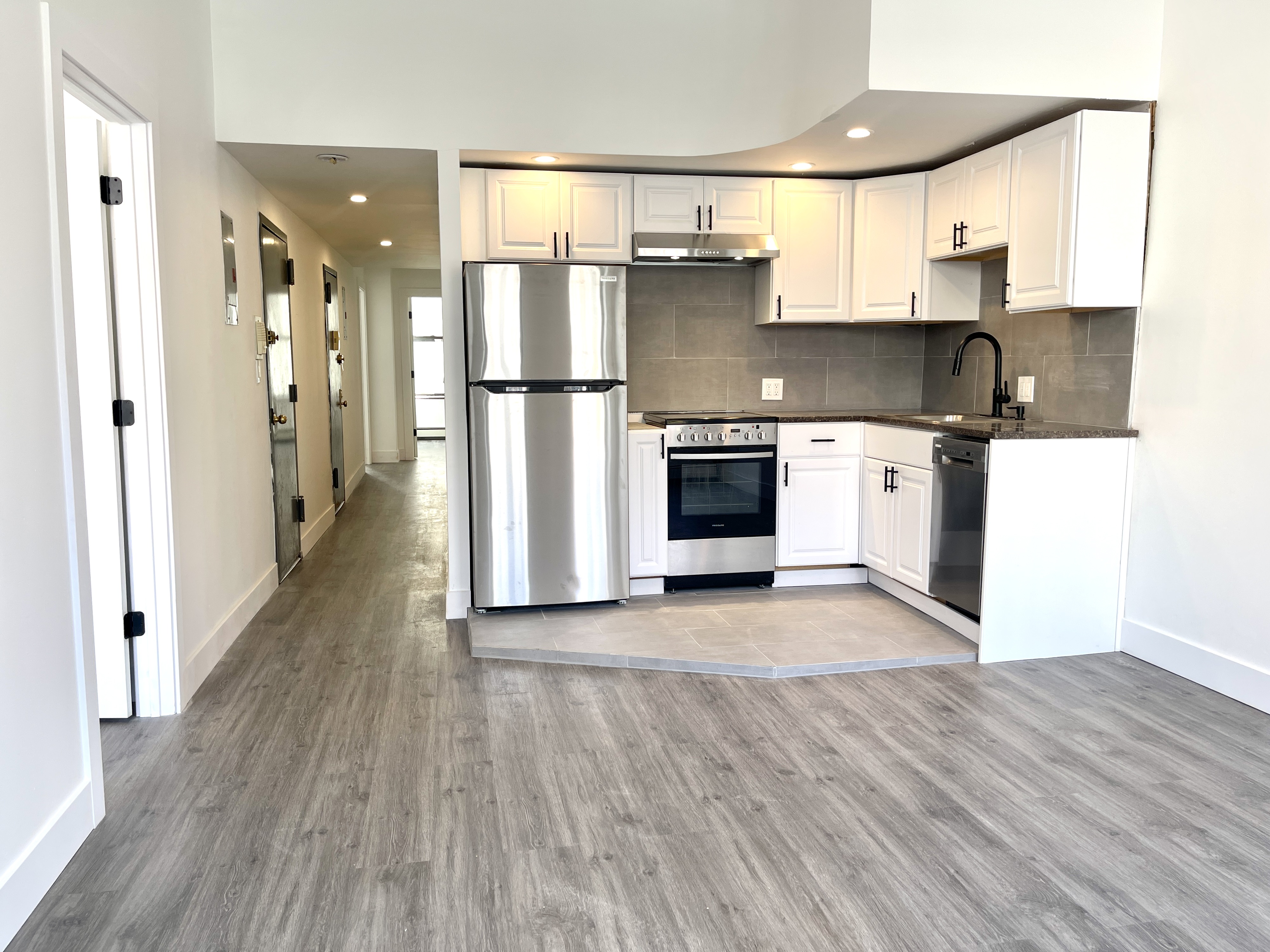 a kitchen with stainless steel appliances granite countertop a refrigerator a stove and a wooden floors