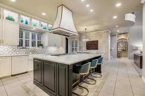 a dining hall with stainless steel appliances kitchen island granite countertop a table chairs and a view of living room