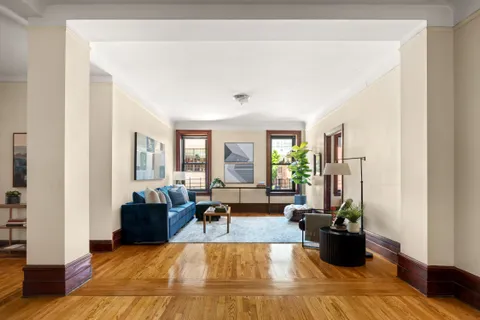 a living room with furniture large window and wooden floor