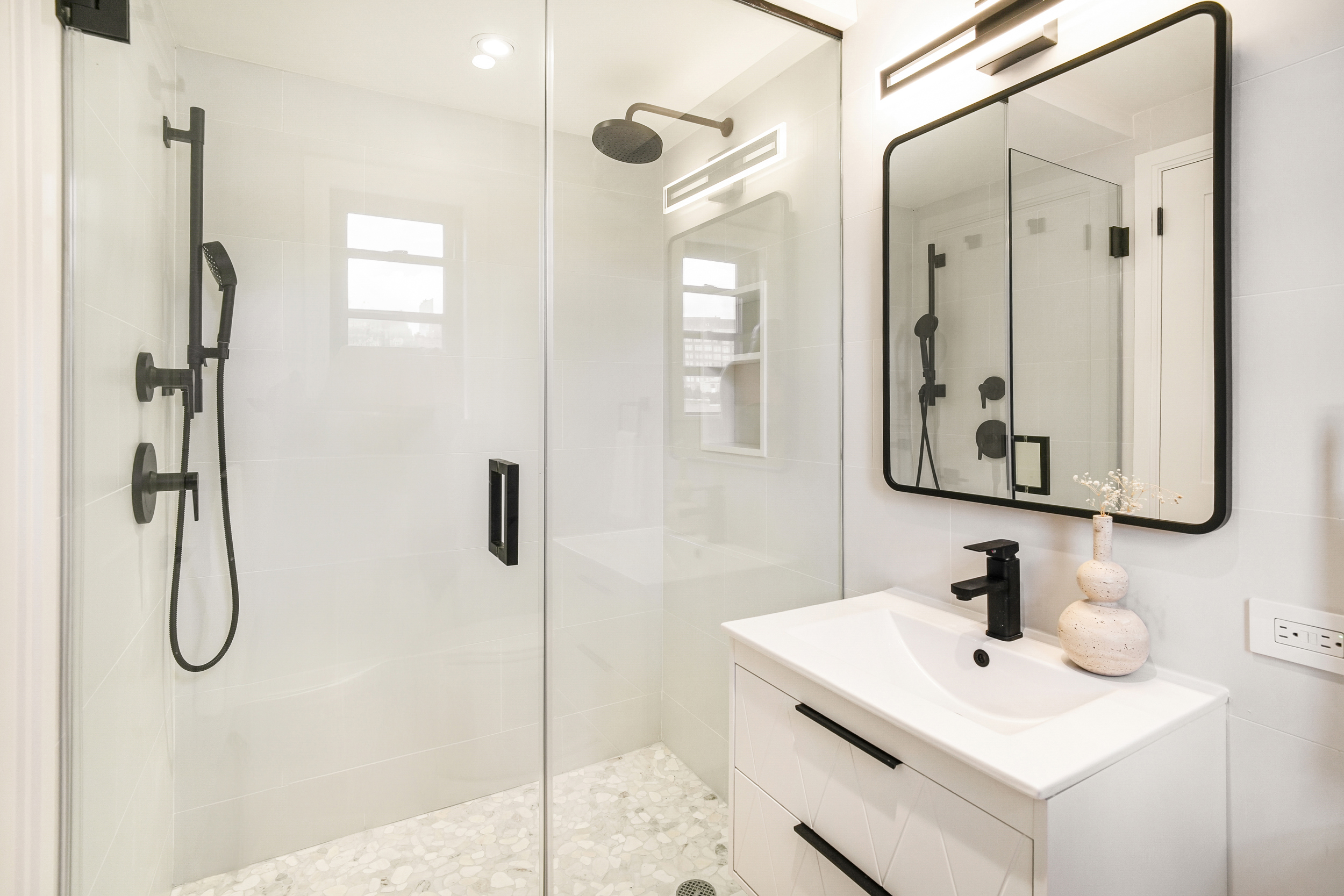 31 Jane Street, Unit 10FG Manhattan, NY 10014 - Photo 20 of 27 a bathroom with a shower sink and mirror