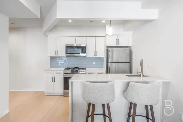 a kitchen with kitchen island granite countertop a sink cabinets and refrigerator