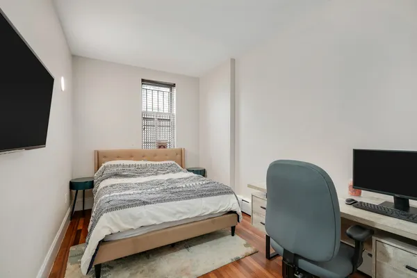 a bedroom with a bed a flat screen tv and a chair