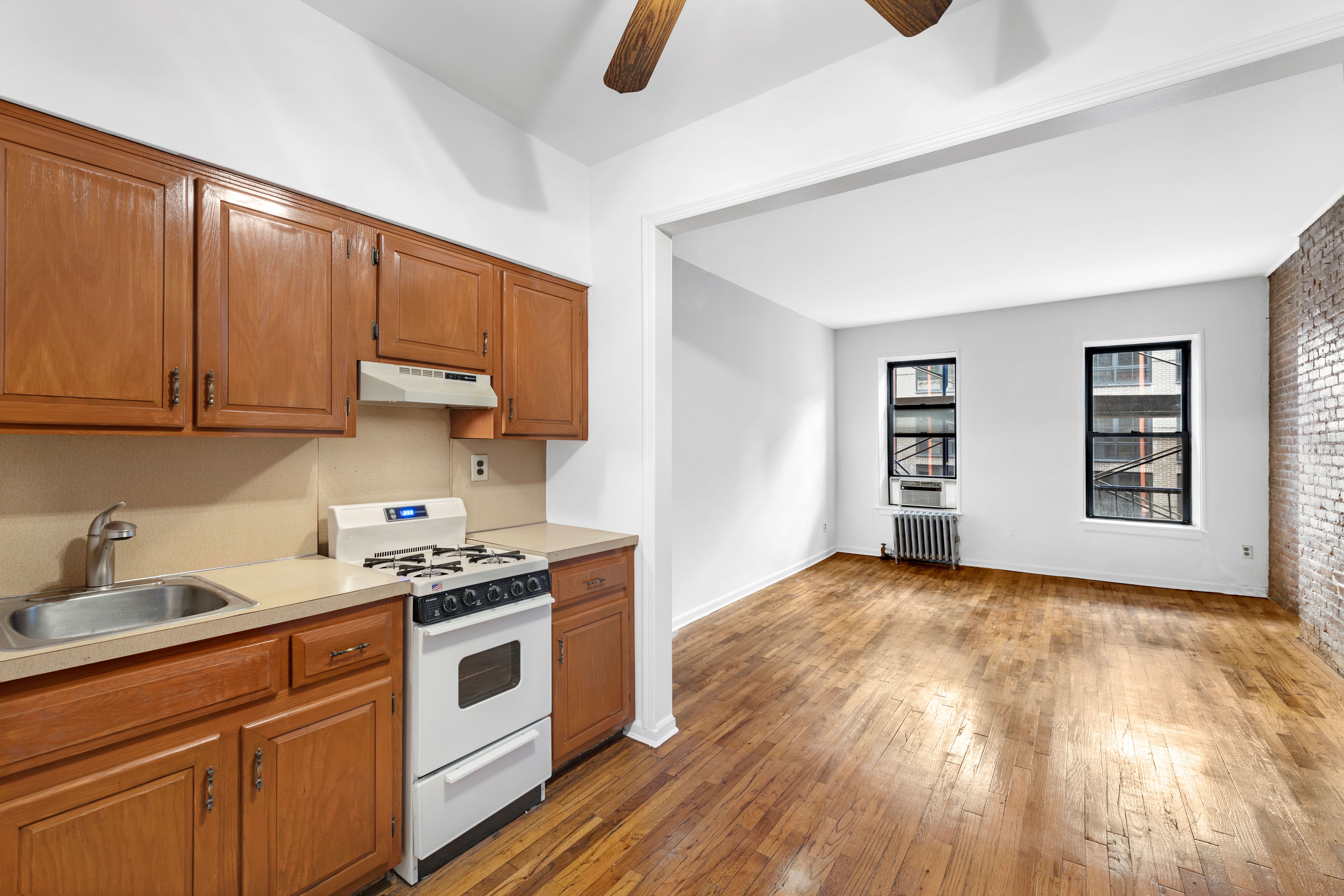 433 West 54th Street, Unit 1 Manhattan, NY 10019 - Photo 5 of 9 a kitchen with granite countertop a stove a sink and a microwave