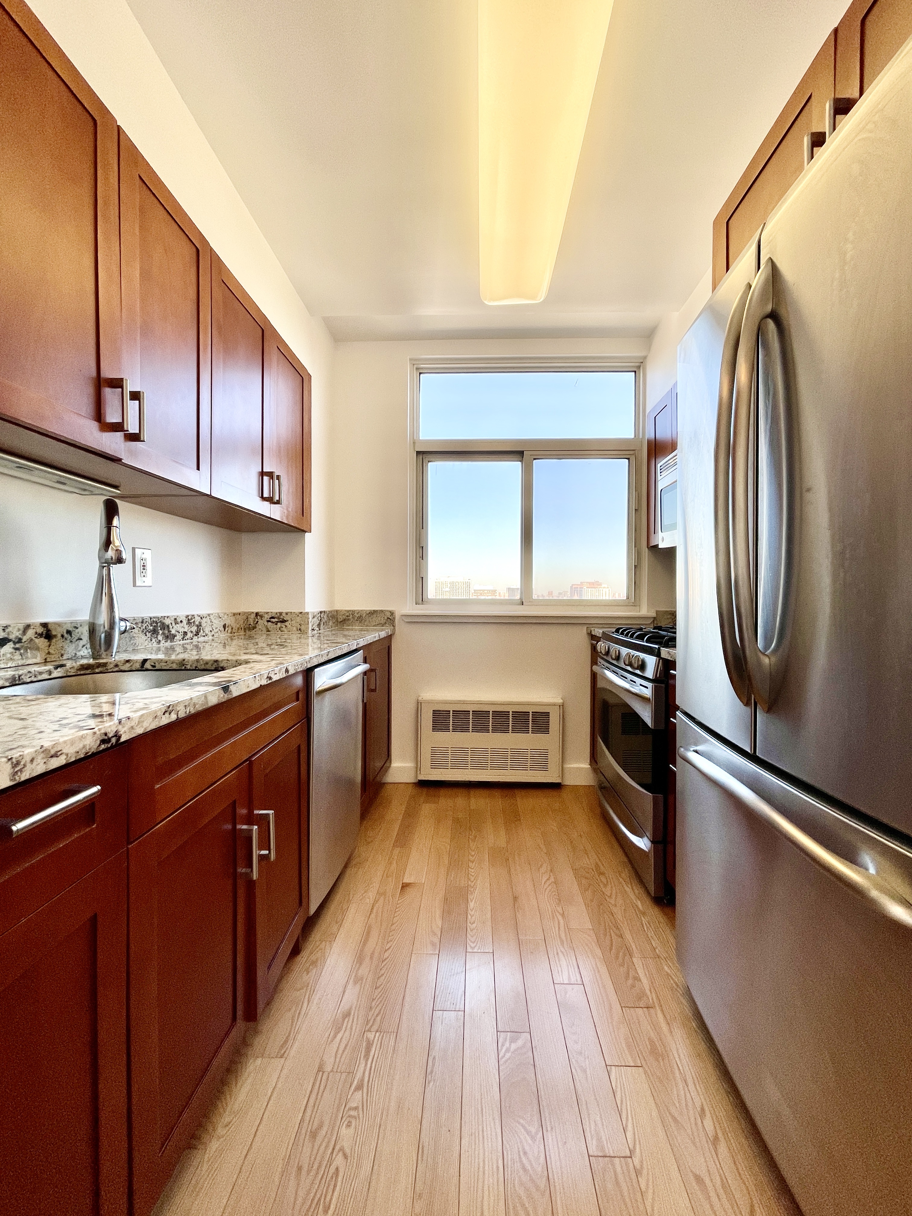 106 West 116th Street, Unit 12A Manhattan, NY 10026 - Photo 3 of 13 a kitchen with a sink a stove wooden floor and stainless steel appliances