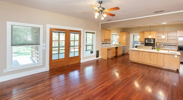 a large kitchen with stainless steel appliances wooden floors and large window