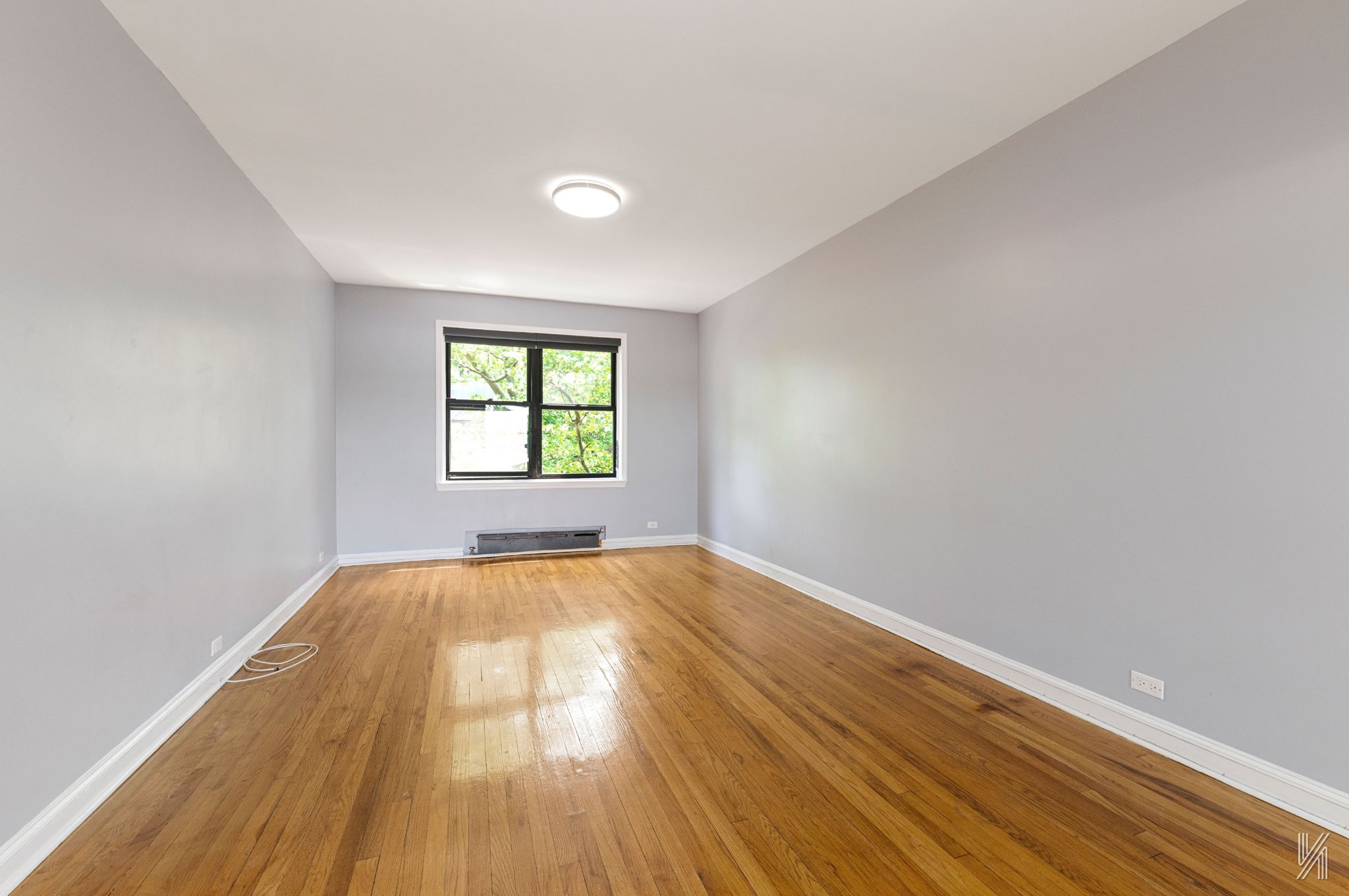 22-20 76th Street, Unit C3 Queens, NY 11370 - Photo 4 of 20 an empty room with wooden floor and windows