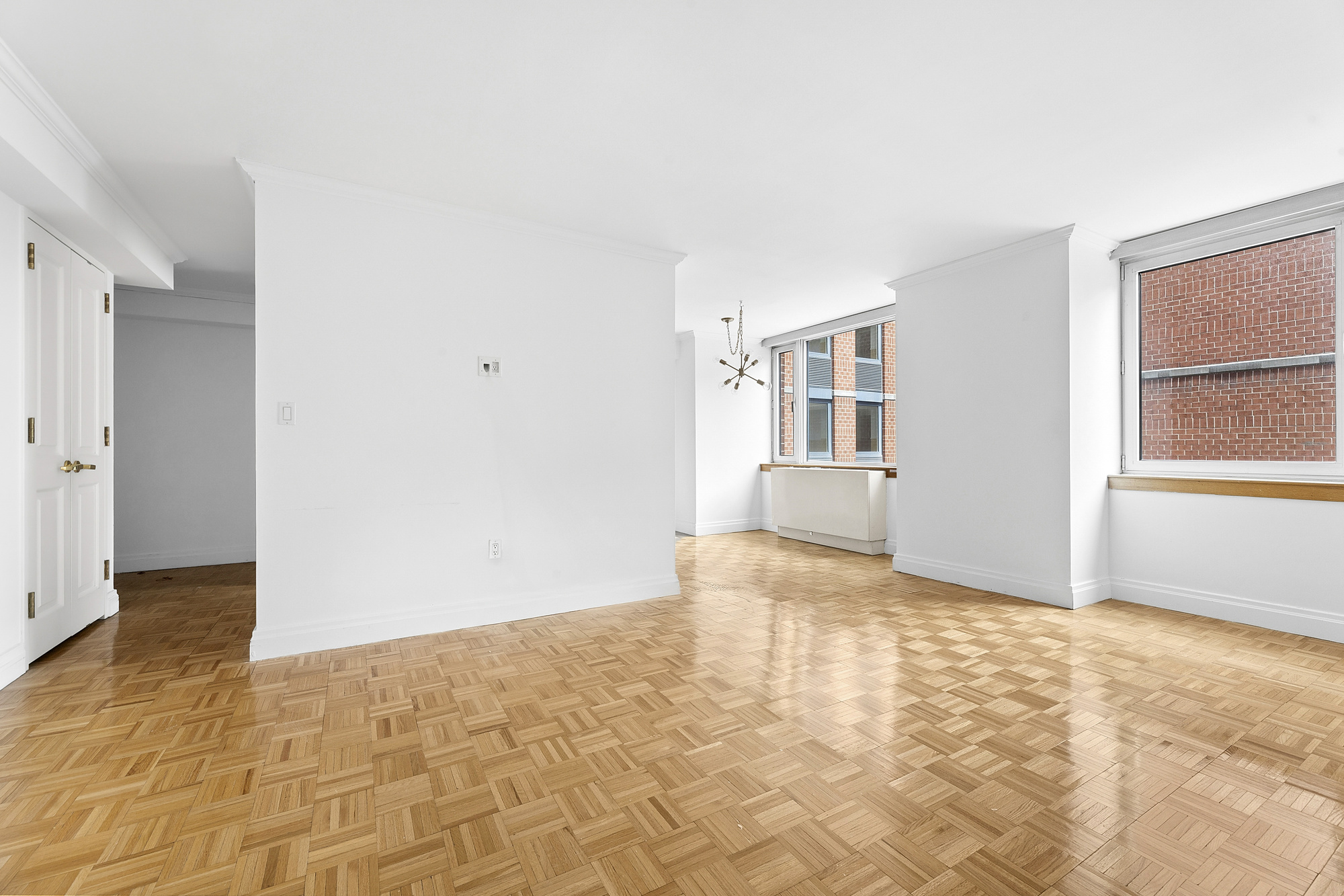 a view of an empty room with window and wooden floor