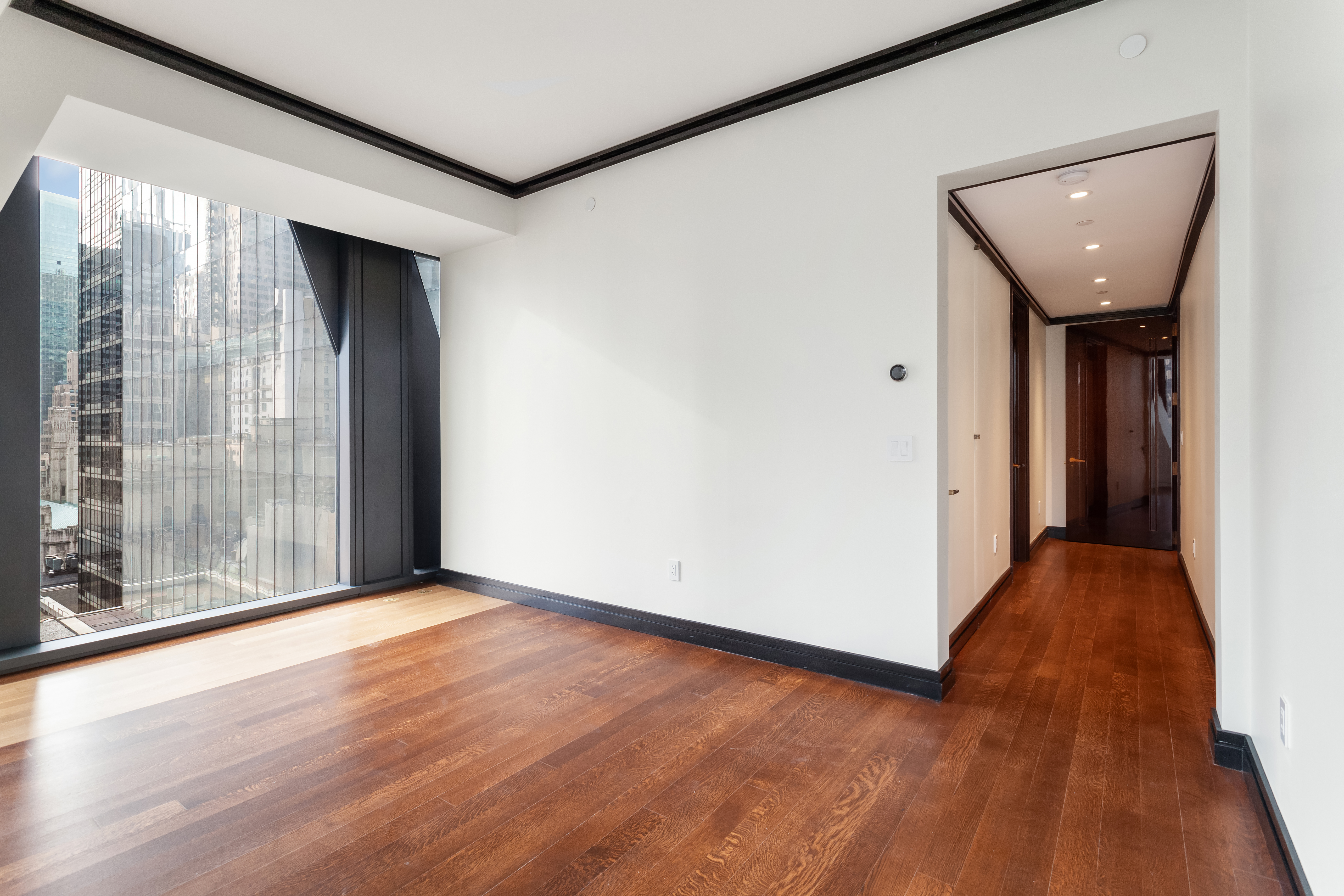 53 West 53rd Street, Unit 16C Manhattan, NY 10019 - Photo 4 of 12 a view of an empty room with wooden floor and a window