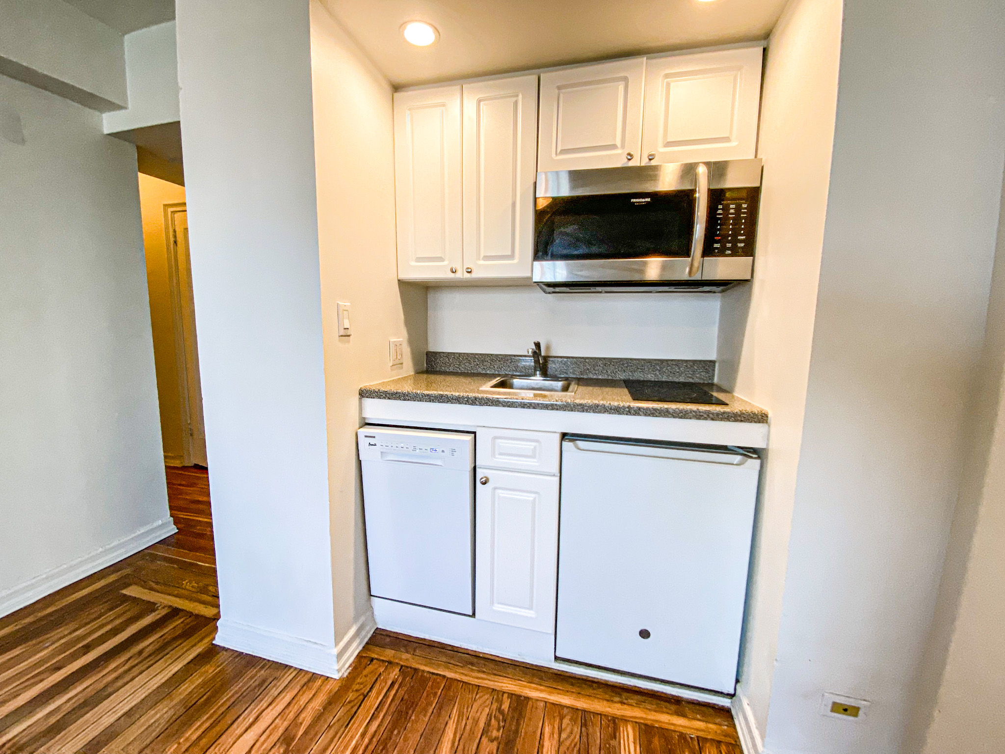 5 Tudor City Place, Unit 627 Manhattan, NY 10017 - Photo 4 of 11 a kitchen with stainless steel appliances a stove a microwave and cabinets
