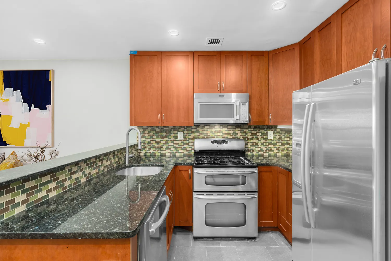 a kitchen with stainless steel appliances granite countertop a refrigerator and a stove top oven