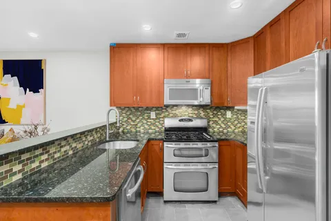 a kitchen with stainless steel appliances granite countertop a refrigerator and a stove top oven
