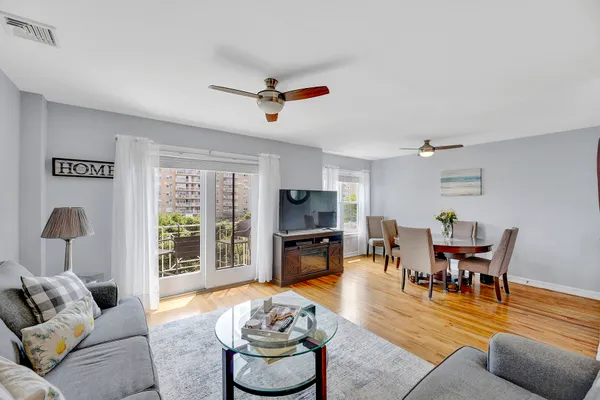 a living room with furniture and a flat screen tv with kitchen view