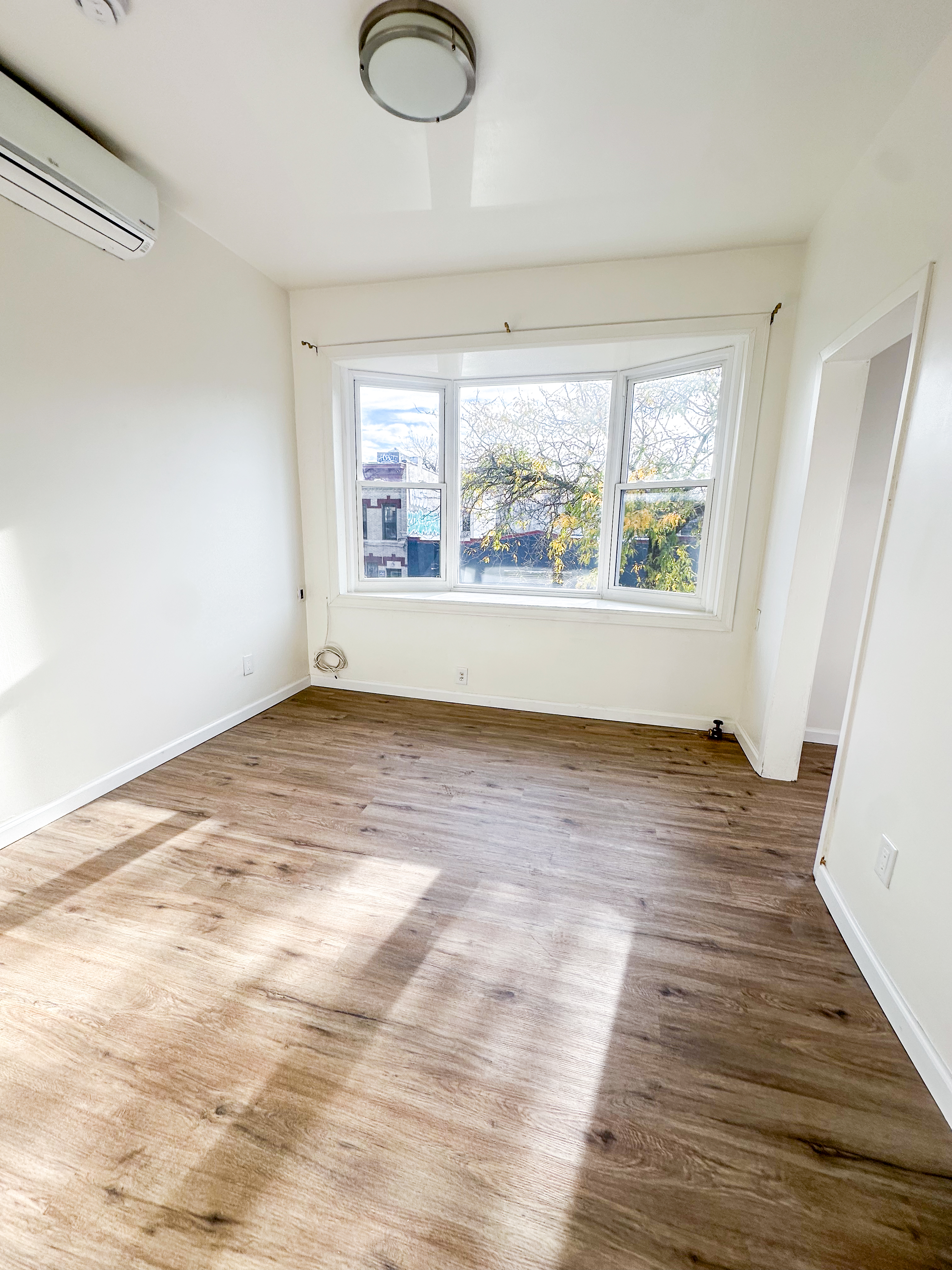 289 A Cooper Street, Unit 2 Brooklyn, NY 11237 - Photo 11 of 19 an empty room with wooden floor and windows