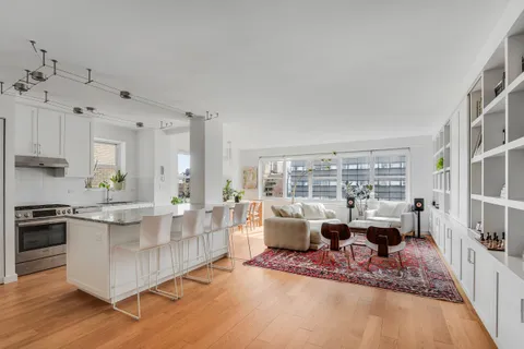 a living room with furniture large windows and wooden floor