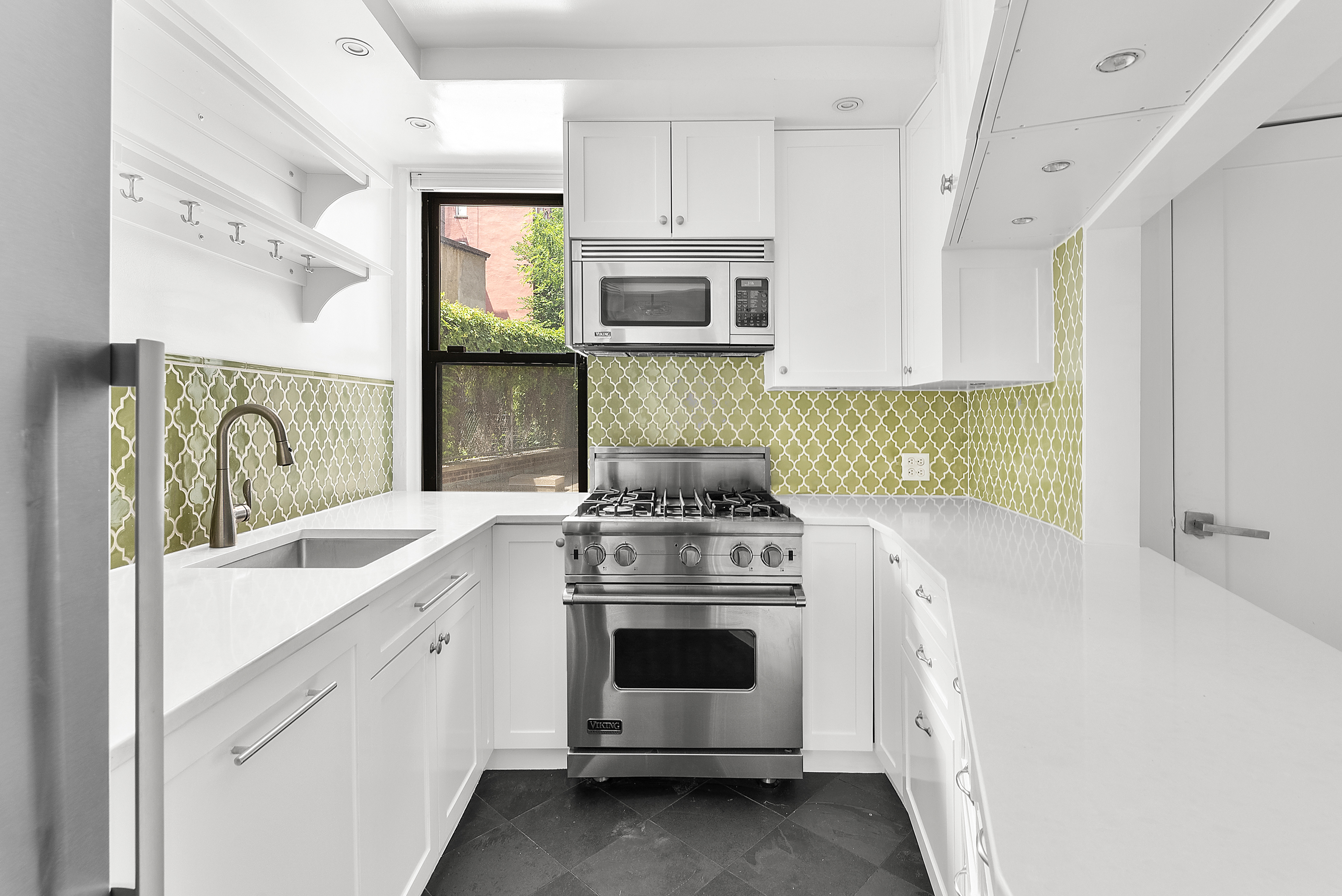 100 Bank Street, Unit 1H Manhattan, NY 10014 - Photo 5 of 10 a kitchen with stainless steel appliances white cabinets and a stove top oven