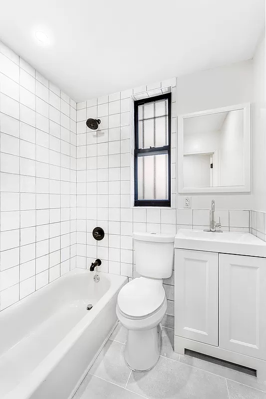 1097 Park Place, Unit 1 Brooklyn, NY 11213 - Photo 7 of 9 a bathroom with a toilet a sink a mirror a bathtub and shower
