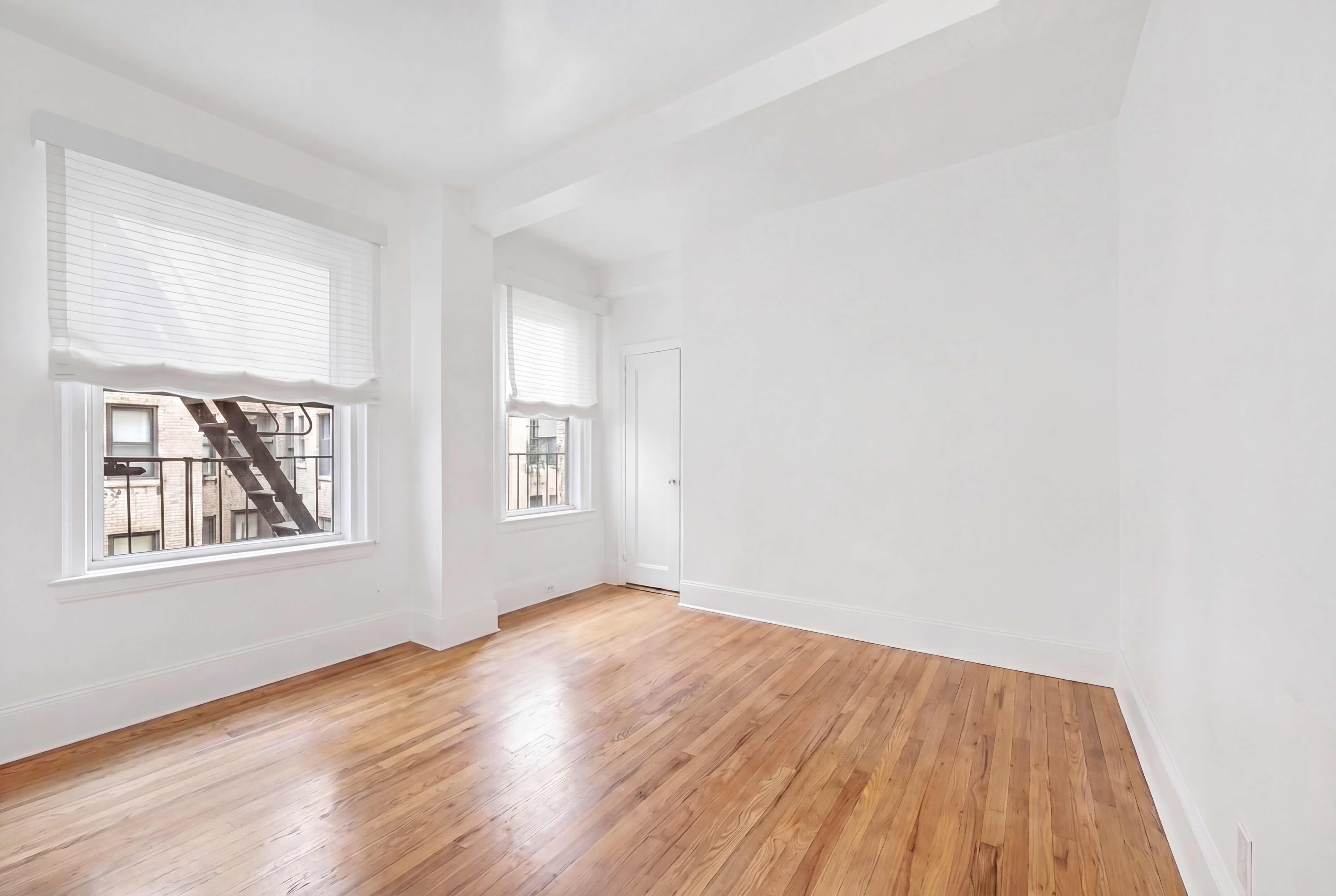 77 Park Avenue, Unit 6H Manhattan, NY 10016 - Photo 4 of 9 an empty room with wooden floor and windows