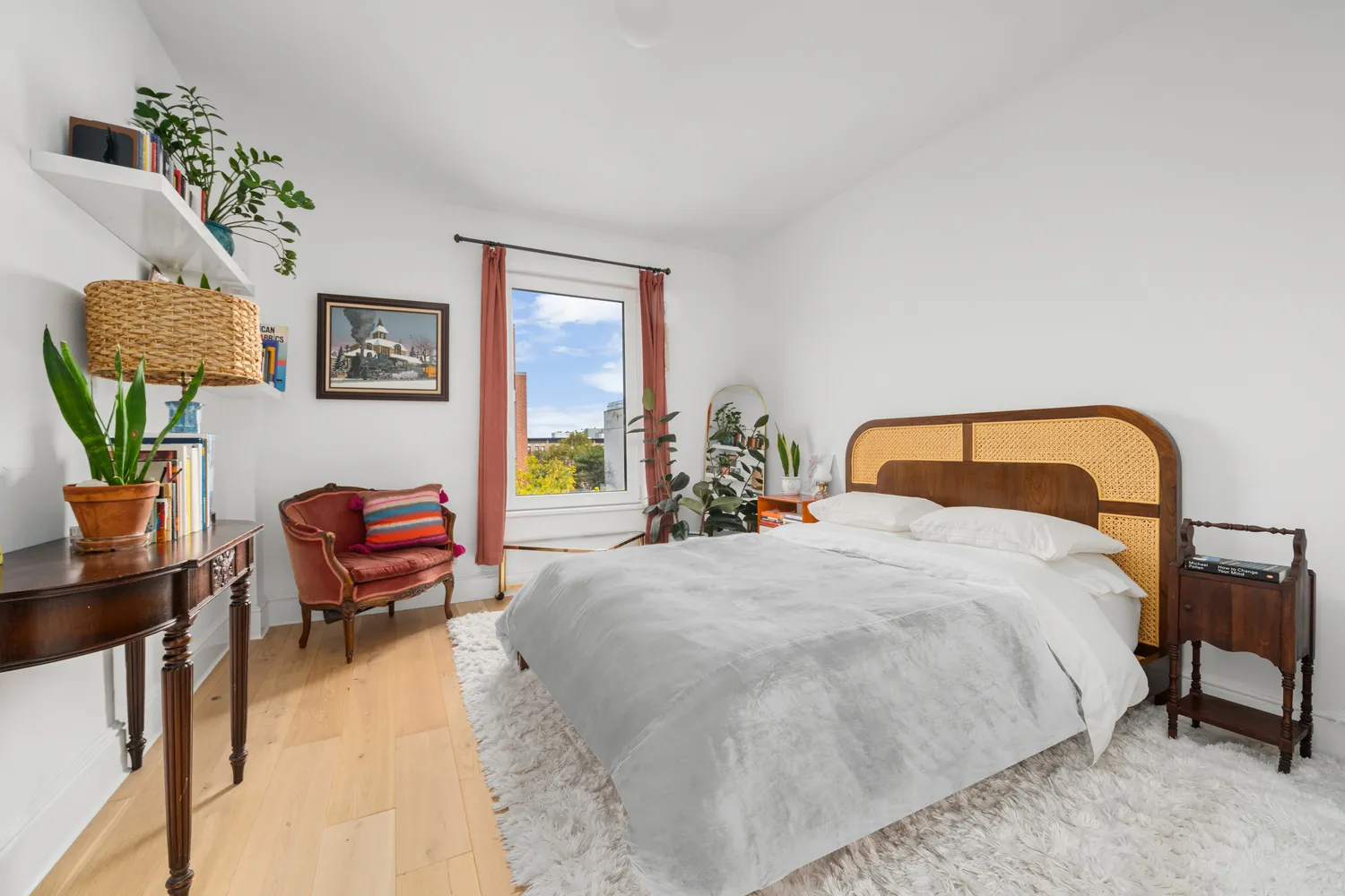 a bedroom with a bed a couch and a potted plant on the dresser
