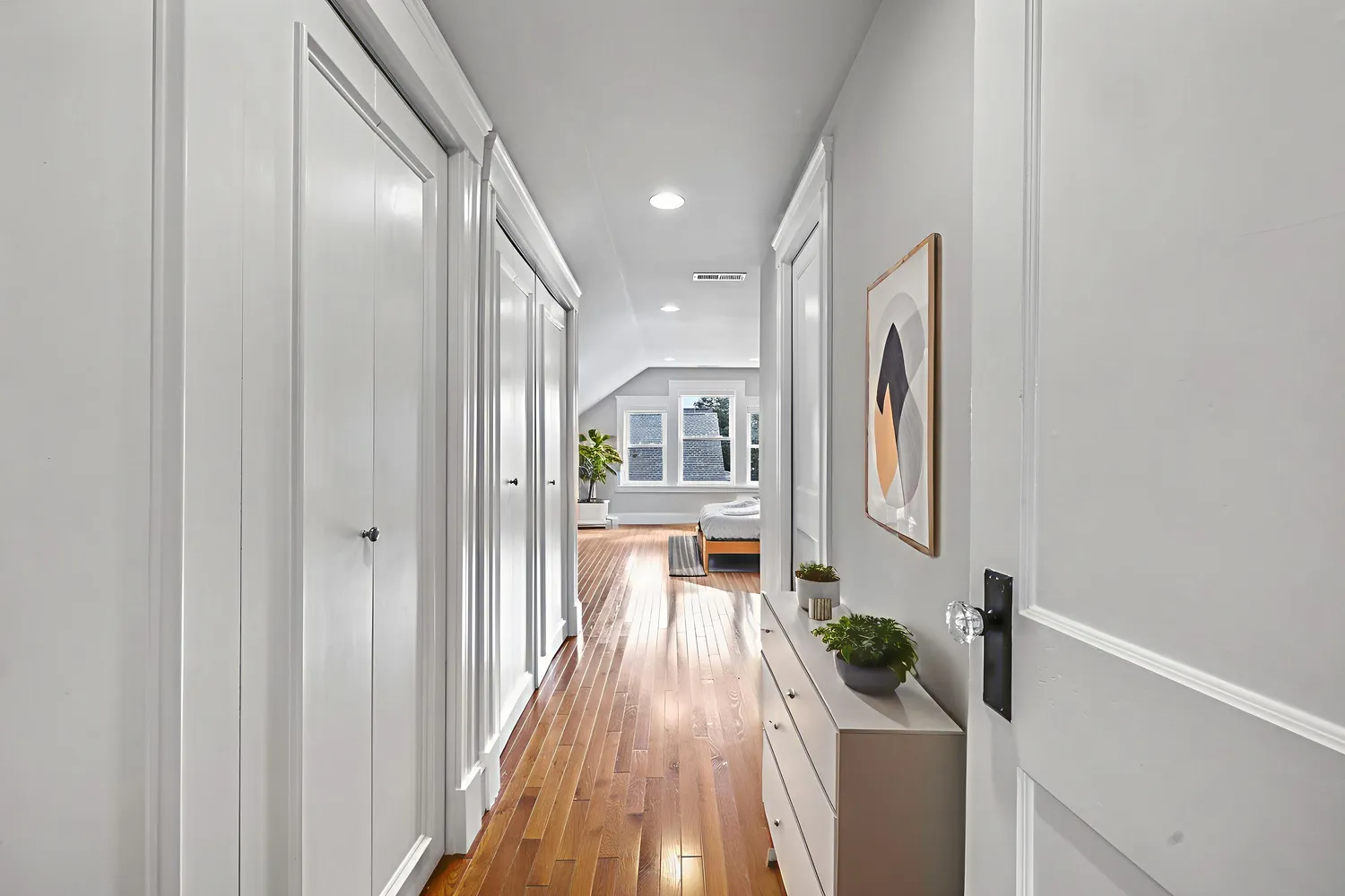 a view of a hallway with wooden floor and a living room