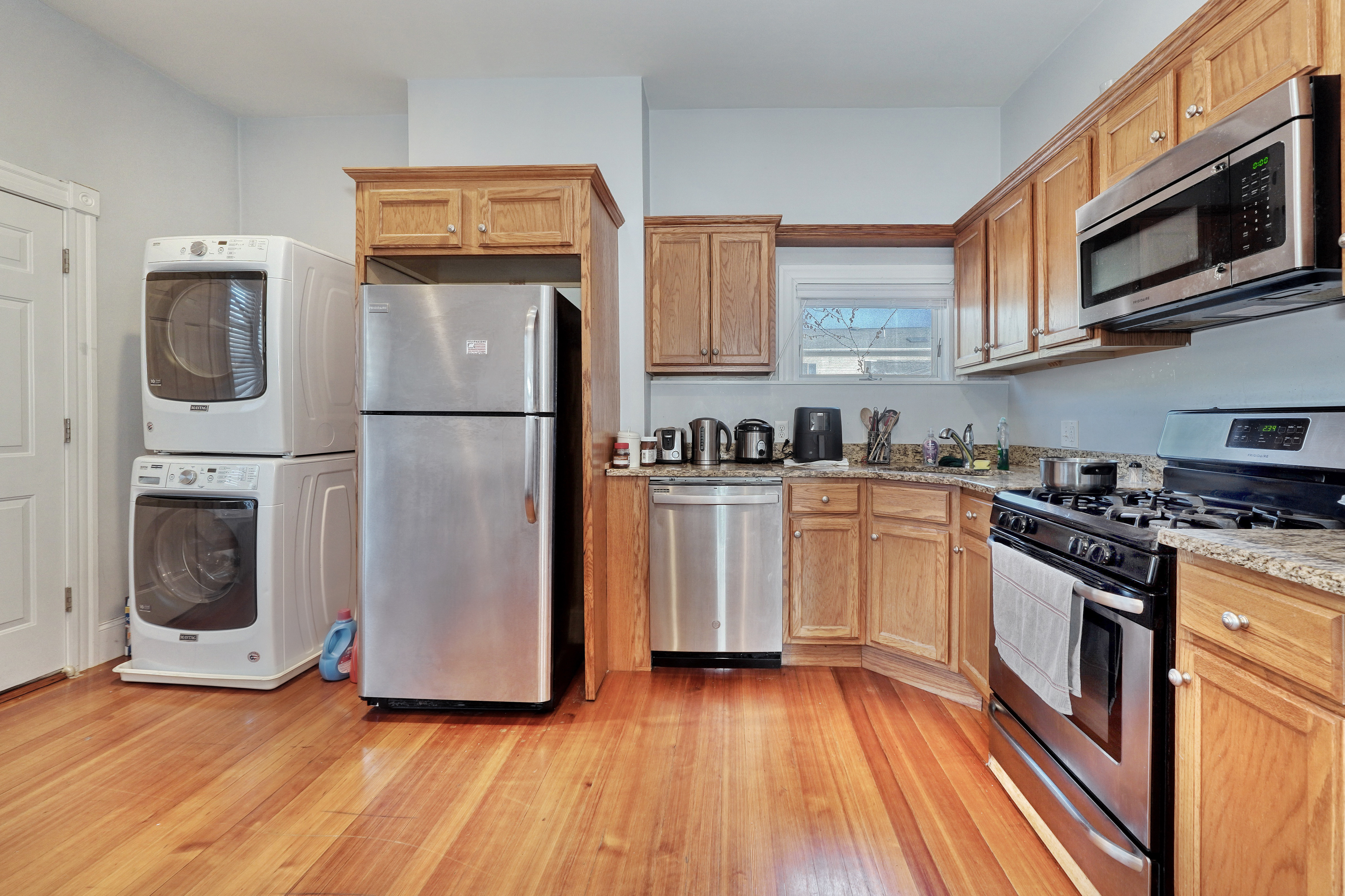 437 High Street Medford, MA 02155 - Photo 4 of 12 a kitchen with granite countertop a refrigerator a stove top oven a sink and dishwasher with wooden floor