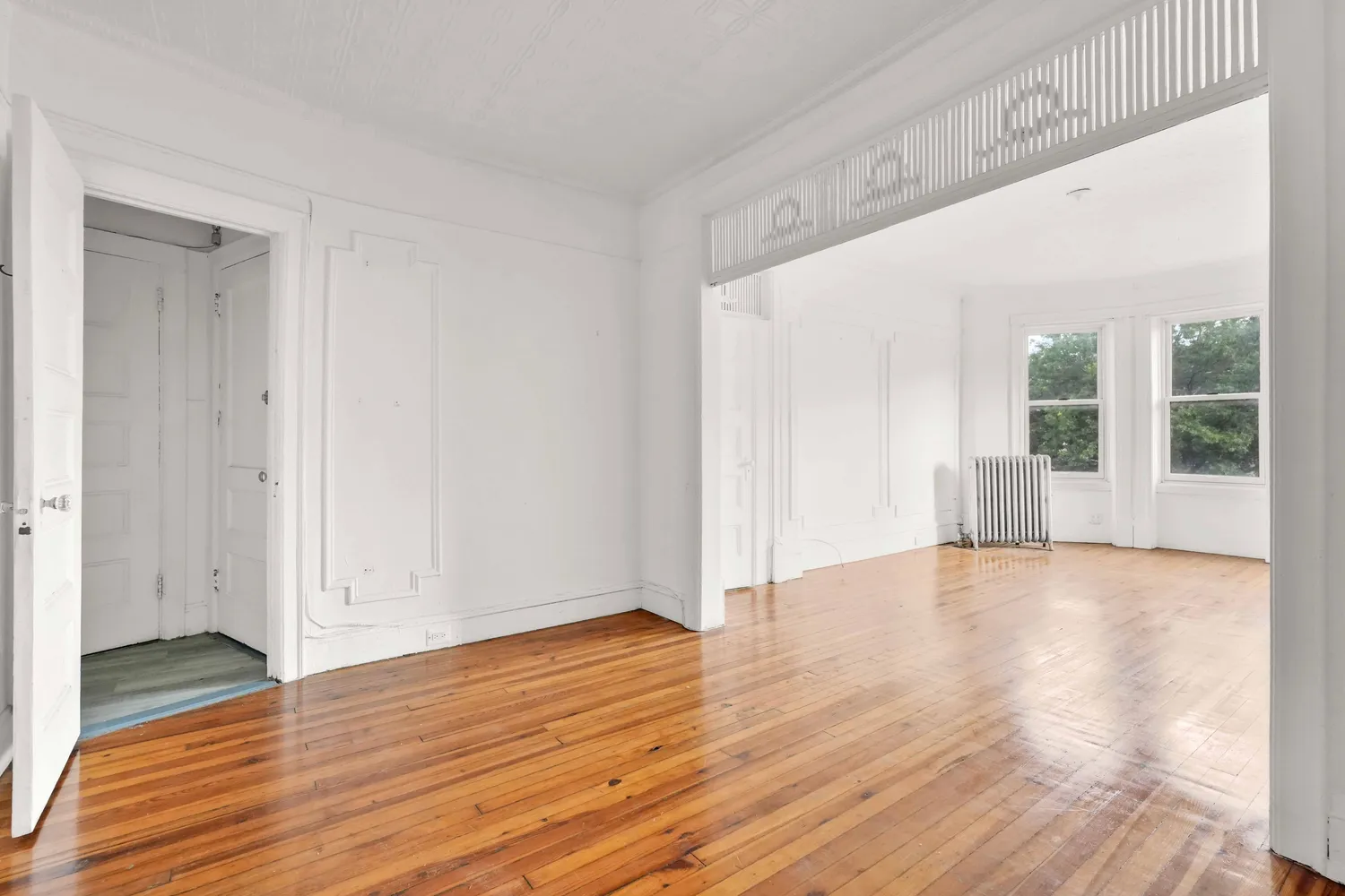 a view of empty room with wooden floor and fan