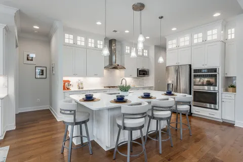 a kitchen with stainless steel appliances kitchen island granite countertop a table chairs and a refrigerator