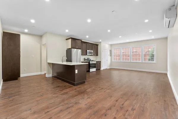 a living room with stainless steel appliances kitchen island hardwood floor and a large window