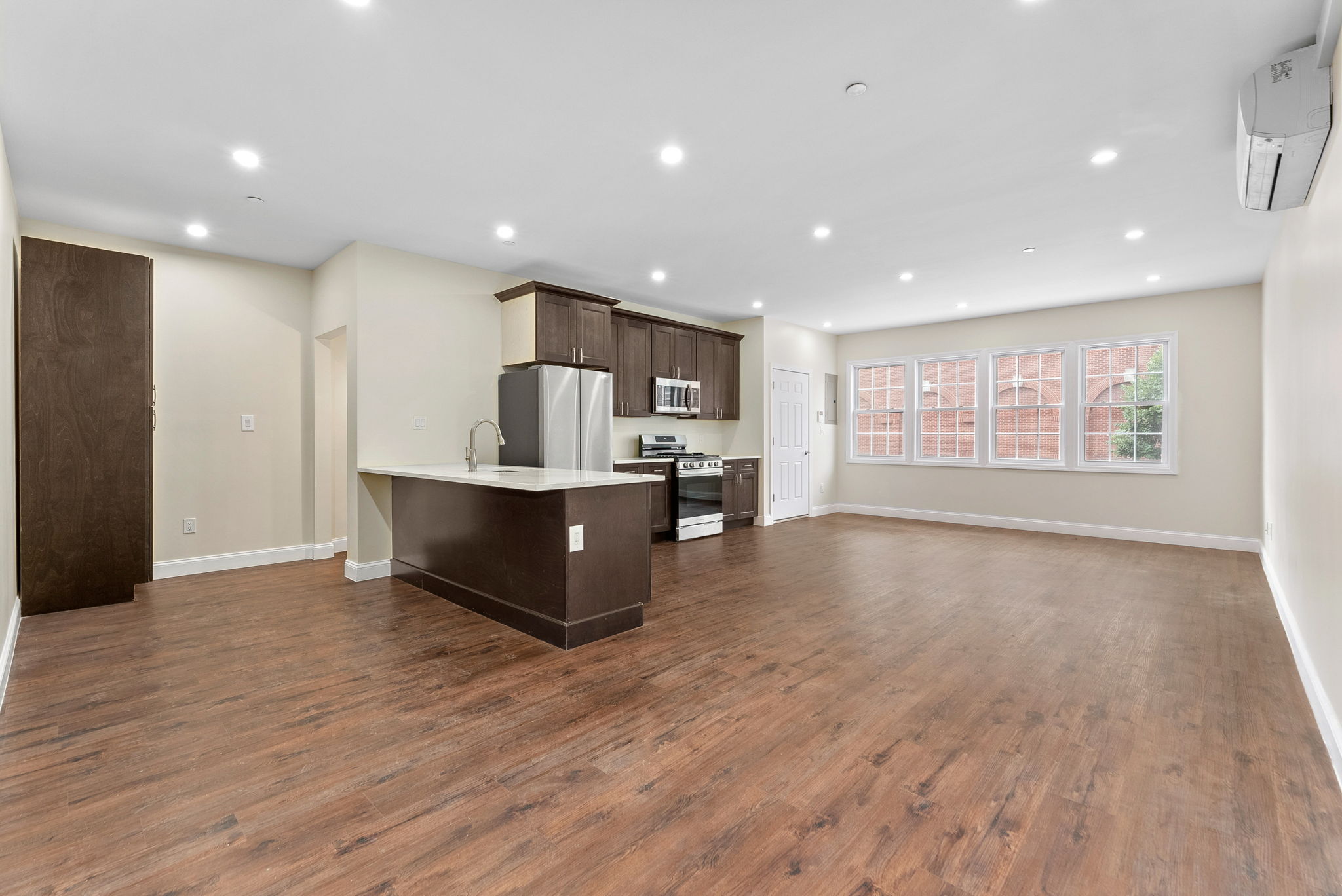 a living room with stainless steel appliances kitchen island hardwood floor and a large window