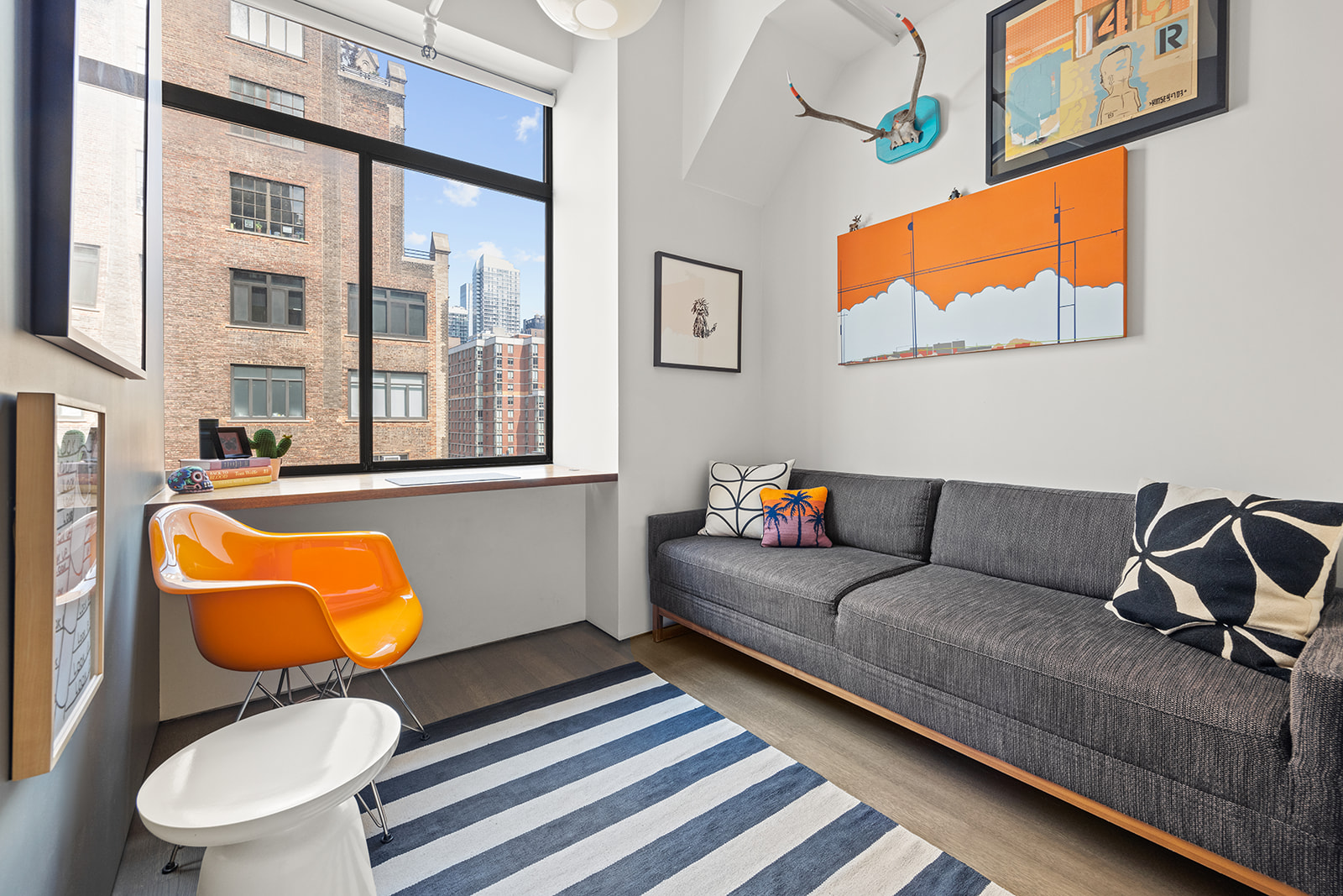 348 West 36th Street, Unit 6N Manhattan, NY 10018 - Photo 8 of 12 a living room with blue couches painting on wall and a large window