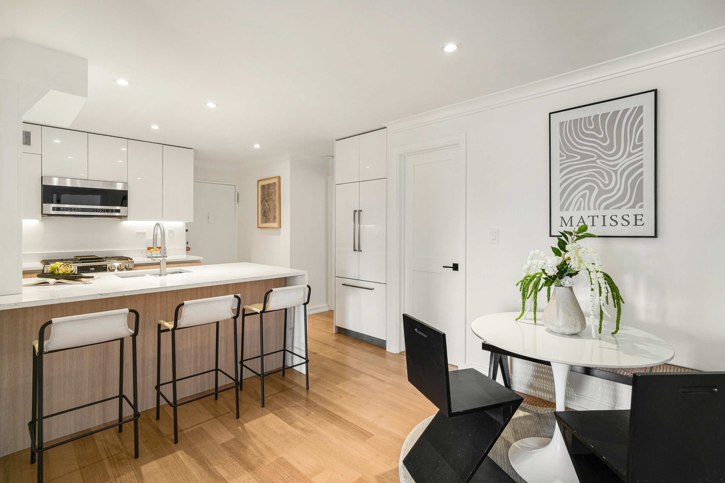 31 Jane Street, Unit 10FG Manhattan, NY 10014 - Photo 9 of 27 a kitchen with stainless steel appliances granite countertop a table chairs and a refrigerator