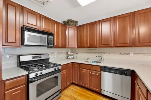 a kitchen with stainless steel appliances granite countertop wooden cabinets stove top oven and sink