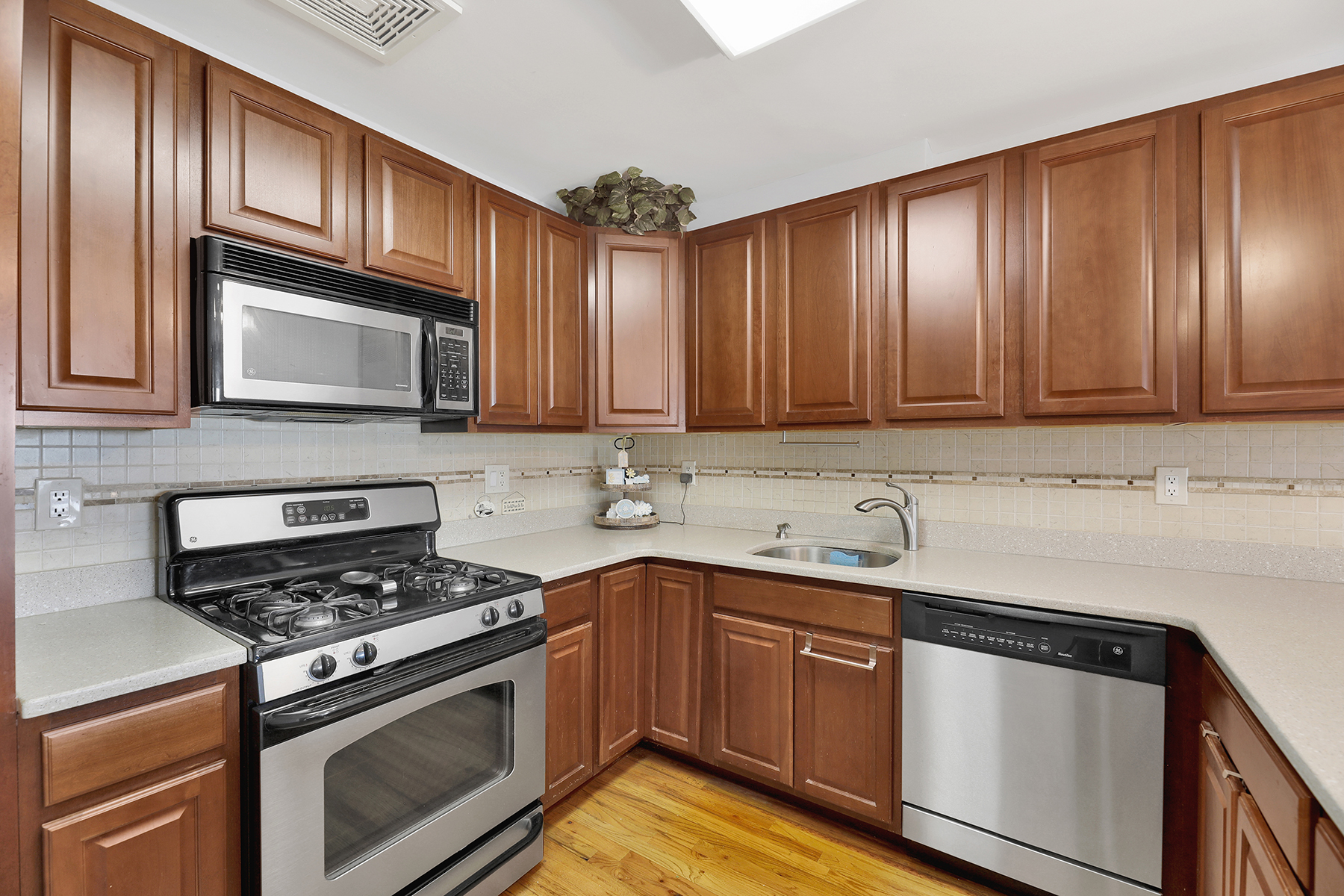 10220 Rockaway Beach Boulevard, Unit 3C Queens, NY 11694 - Photo 12 of 46 a kitchen with stainless steel appliances granite countertop wooden cabinets stove top oven and sink