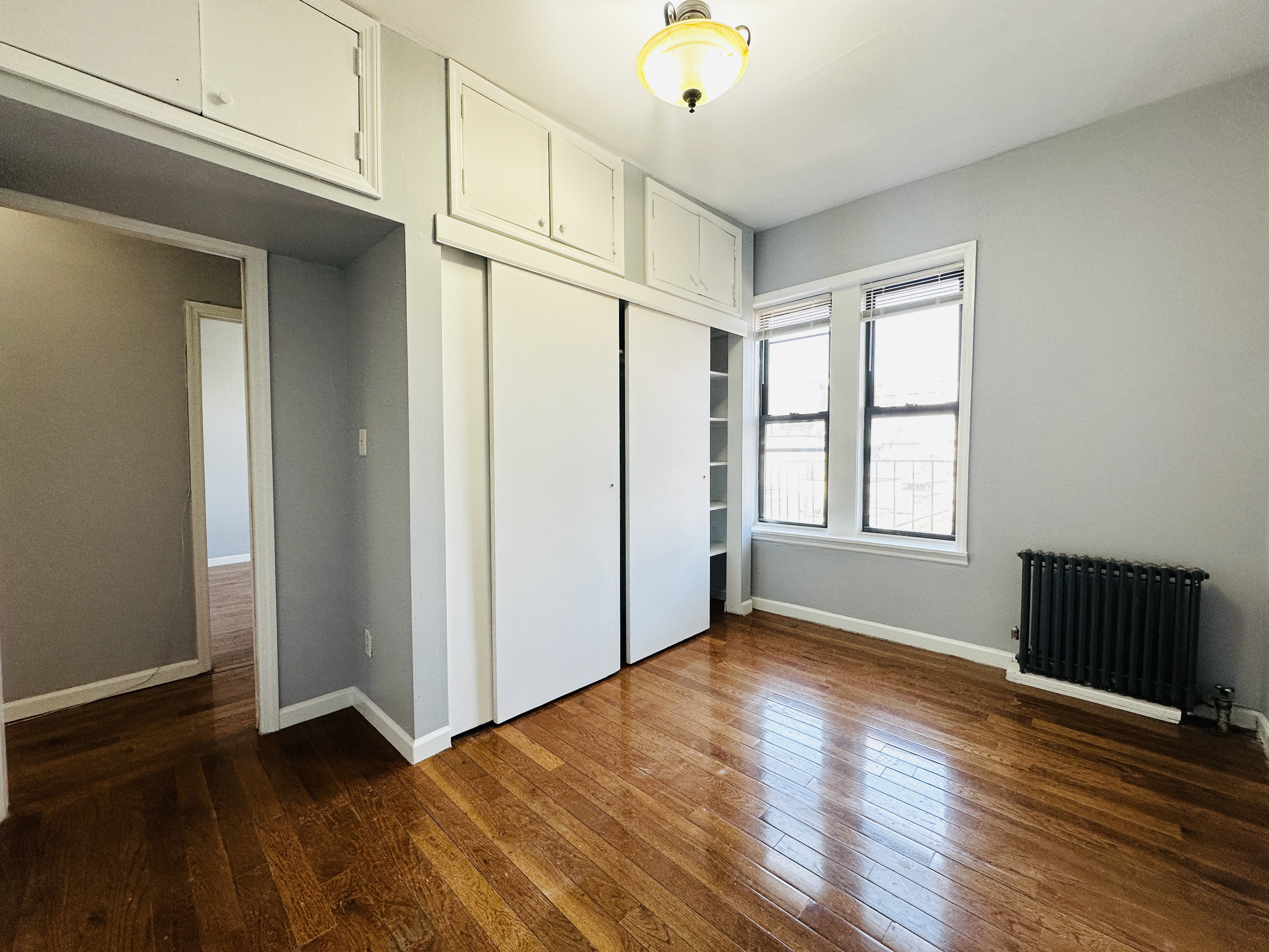 an empty room with wooden floor and windows